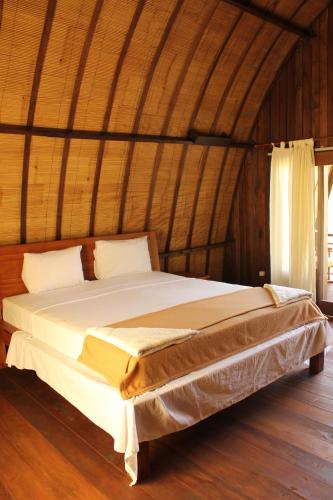 a large bed in a room with a wooden floor at Melati Cottage in Gili Trawangan