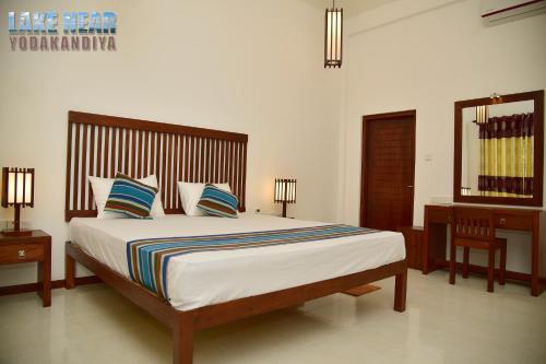 a bedroom with a large bed with two tables and a mirror at Lake Near in Tissamaharama