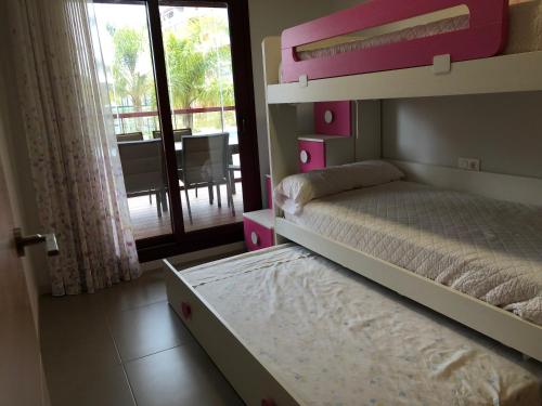 - une chambre avec des lits superposés roses et un balcon dans l'établissement Bajo 2 del Edificio Lucerna III - Mil Palmeras, à Pilar de la Horadada