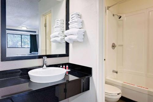 a bathroom with a sink and a toilet and a mirror at Travelodge by Wyndham College Park in Atlanta