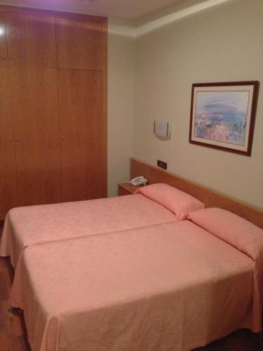 a bedroom with a large bed with pink sheets at Hotel Pelayo in Barcelona