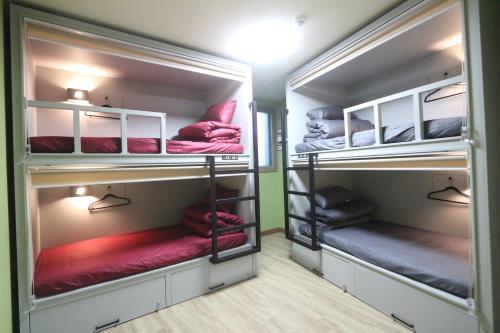 a room with three bunk beds with red pillows at Daegu Midtown Hostel in Daegu
