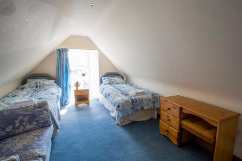 une chambre mansardée avec deux lits et une table dans l'établissement Dairy Cottage, à Ayr