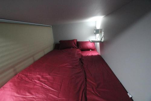 a small room with a red bed in the corner at Daegu Midtown Hostel in Daegu