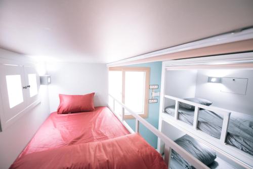 a small room with a red bed and a window at Daegu Midtown Hostel in Daegu