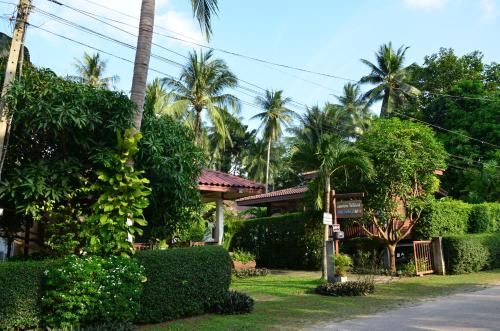 a house with bushes and palm trees and a street at Sean Sabai Home e Ristobar in Taling Ngam Beach