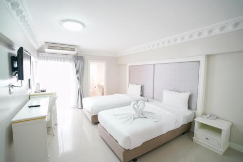 ein weißes Schlafzimmer mit 2 Betten und einem Band darauf in der Unterkunft Romance Hotel Sukhumvit 97 in Bangkok