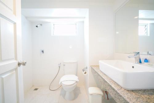 een witte badkamer met een toilet en een wastafel bij Romance Hotel Sukhumvit 97 in Bangkok