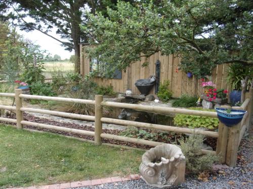 una recinzione di legno in un giardino con una statua di La Pastourelle Chambre d Hôtes a Saint-Méloir-des-Ondes