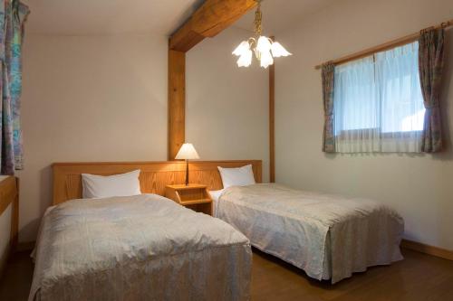 a bedroom with two beds and a lamp and a window at Izumigo AMBIENT Azumino Cottage in Azumino