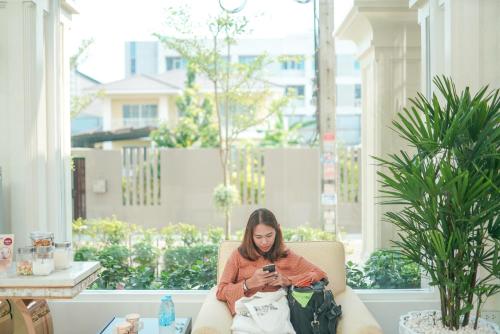 a woman sitting in a chair looking at her cell phone at Romance Hotel Sukhumvit 97 in Bangkok