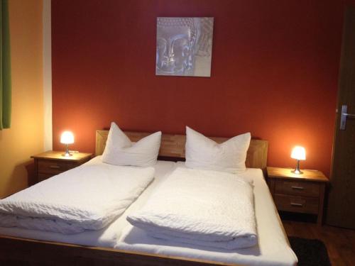a bedroom with two beds with white sheets and two lights at Pension Gisela in Gößweinstein