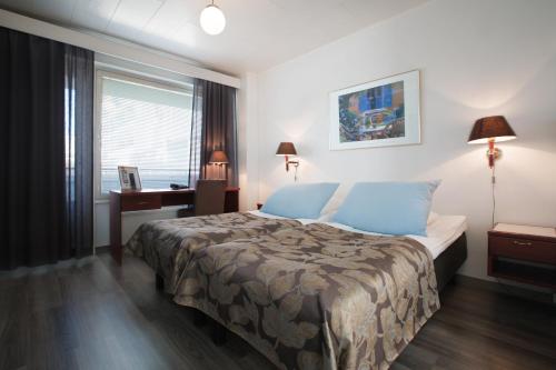 um quarto com uma cama, uma secretária e uma janela em Hotel Milton em Jyväskylä