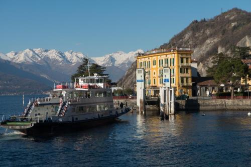 a large boat in the water next to a building at Hotel Olivedo in Varenna
