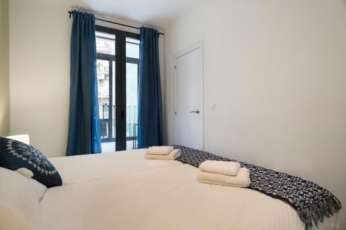 1 dormitorio con 1 cama blanca grande y cortinas azules en Stay U-nique Apartments Rossello, en Barcelona