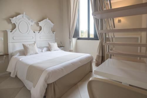 a white bedroom with a white bed and a window at Palazzo Belsanti in Lecce