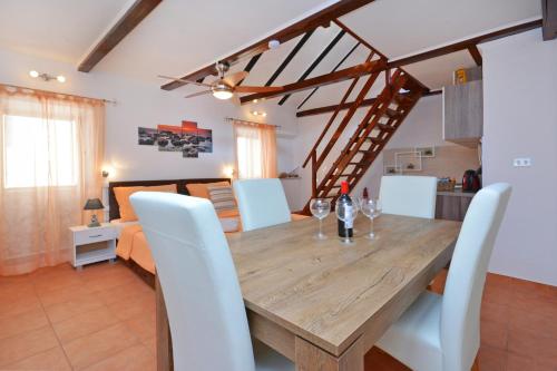 a dining room with a wooden table and white chairs at Apartments & Rooms As in Vis