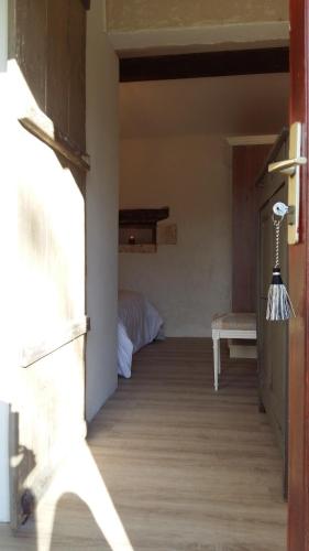 a hallway with a room with a bed and a door at Le gîte des chambres de la grange in Cherval