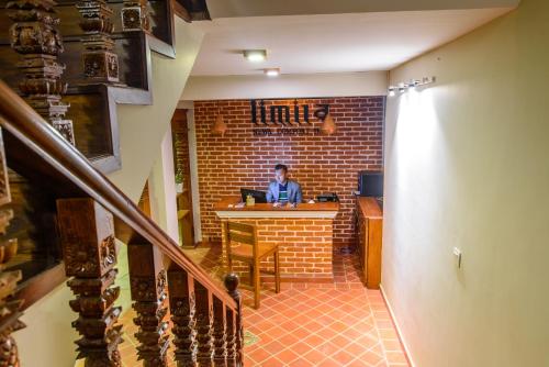 a man sitting at a counter in a brick room at Hotel Timila in Pātan