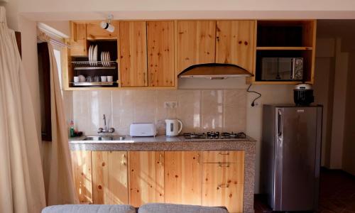 a kitchen with wooden cabinets and a stainless steel refrigerator at Hotel Timila in Pātan