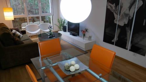 ミヤドイロにあるApartamentos Antares 1のリビングルーム(ガラステーブル、オレンジの椅子付)