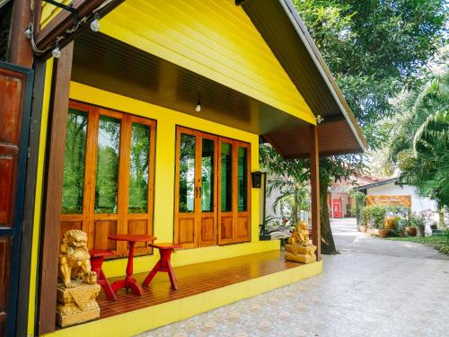 a yellow house with a wooden porch with a table at Moradok Thai Guesthouse in Phra Nakhon Si Ayutthaya
