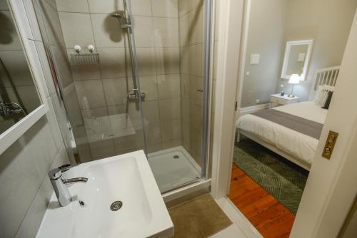 a bathroom with a shower and a sink and a bed at Casa Conforto in Ponta Delgada