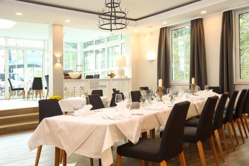 a dining room with white tables and chairs and windows at Landhotel Potsdam in Potsdam
