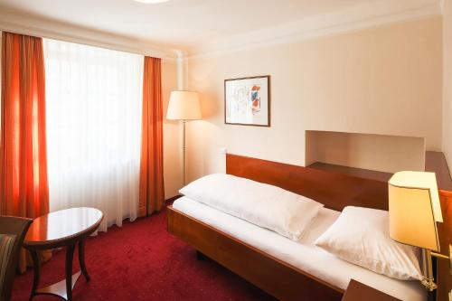 a hotel room with a bed and a table and a chair at Ambiance Hotel - Braunau - Simbach in Braunau am Inn