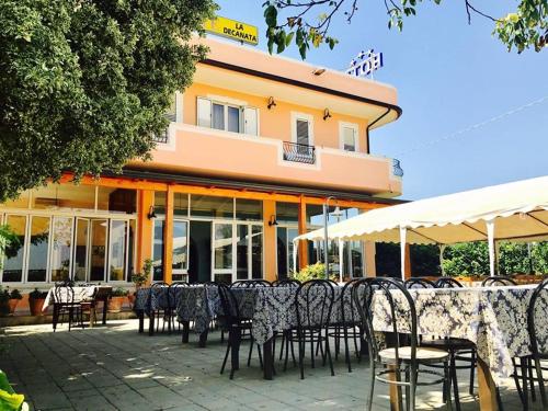 un grupo de mesas y sillas frente a un edificio en Hotel Ristorante La Decanata, en Le Castella