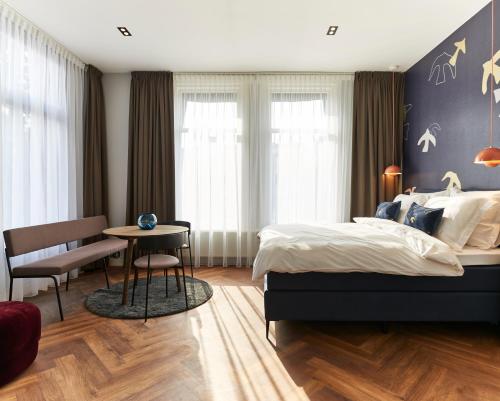 a bedroom with a bed and a table and a chair at Hotel Pistache Den Haag in The Hague