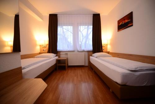two beds in a room with a window at Hotel Linde Stuttgart in Stuttgart