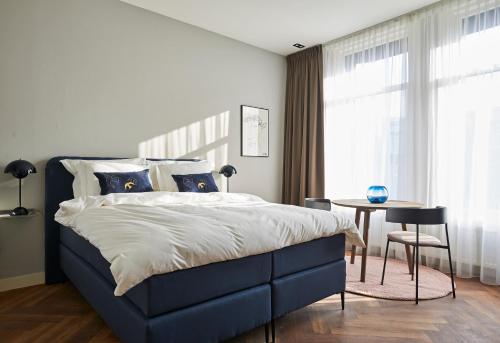 a bedroom with a bed and a table and a window at Hotel Pistache Den Haag in The Hague