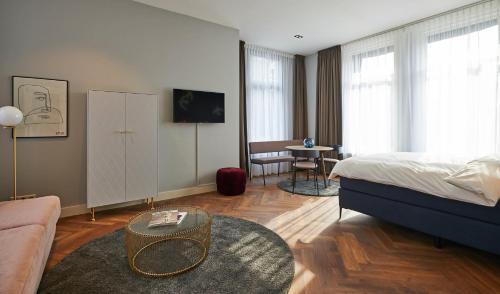 a bedroom with a bed and a couch and a table at Hotel Pistache Den Haag in The Hague