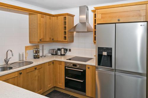 La cuisine est équipée d'armoires en bois et d'un réfrigérateur en acier inoxydable. dans l'établissement 37A Commerce Street, à Lossiemouth