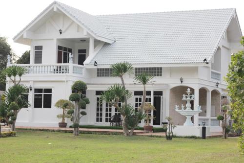 una casa blanca con palmeras delante en HOME@HOSTEL KANCHANABURI, en Kanchanaburi