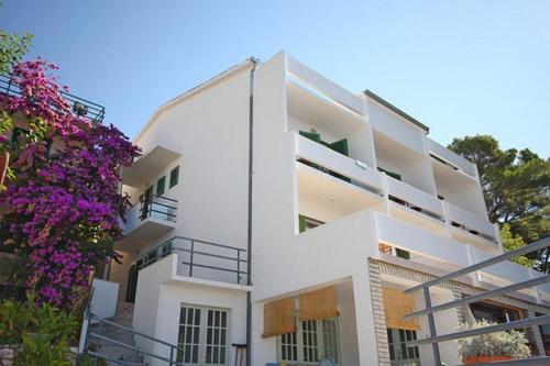 a white building with a balcony and purple flowers at Garni IVANAC in Brela
