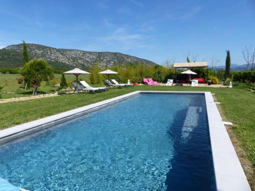 una piscina in un cortile con sedie e ombrelloni di Chambre d'hôtes du Mas de Longuefeuille a Malaucène