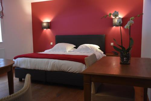 um quarto com uma cama grande e uma parede vermelha em Hotel Le Moulin Simonis em Laforêt