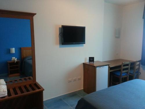 a room with a bed and a desk and a television on the wall at Serpa Hotel in Anzio