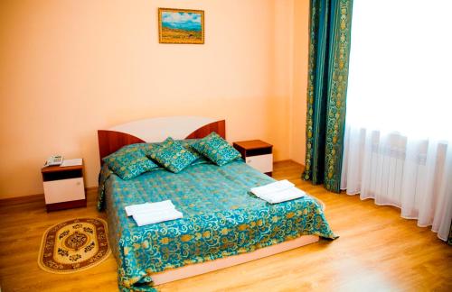 a bedroom with a bed with a blue comforter at Hotel Nurlytau in Borovoye