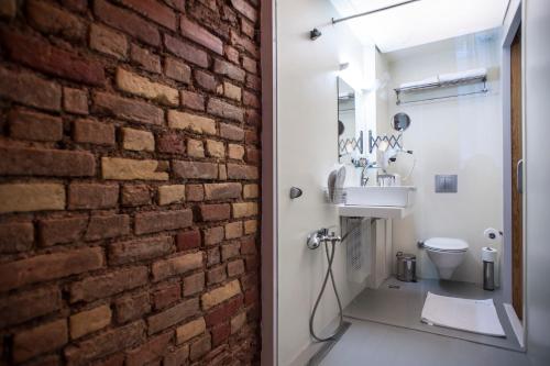 a brick wall in a bathroom with a toilet and sink at Peradays in Istanbul