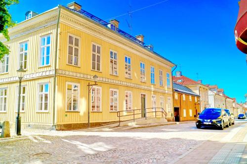 a yellow building with a car parked in front of it at Vänerport Lakefront Hotell in Mariestad