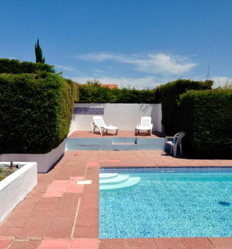 a swimming pool with two lounge chairs next to a hedge at Wavin' Trees Ericeira in Ericeira