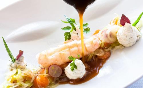 une assiette blanche de nourriture avec des crevettes à la sauce dans l'établissement Appartement Cap Sud Vue Mer à 30m de la Plage, à Wimereux