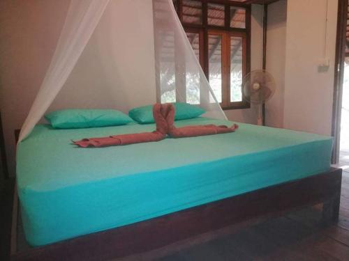 a large bed with a blue bedspread with aopus at Cashew Nut Bungalow, Ko Mook in Koh Mook