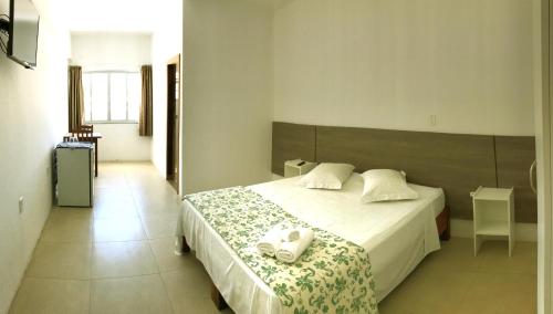 a bedroom with a bed with two towels on it at Hotel Pousada Santos in Pinheira