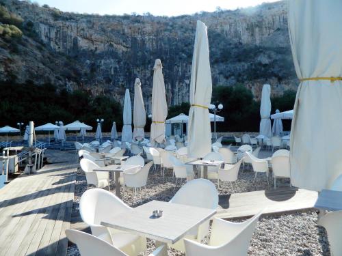 a bunch of tables and white chairs and umbrellas at Sounio Palea Heaven in Palaiá Fókaia