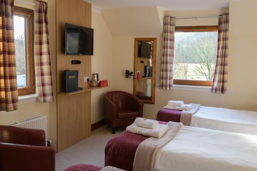 a hotel room with two beds and a chair at Bracarina House Bed & Breakfast & Caledonian Studio in Invermoriston