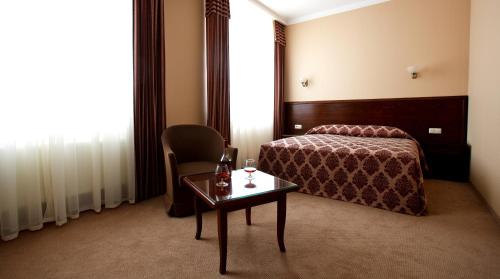 ティラスポリにあるCityClub Hotelのベッド、テーブル、椅子が備わるホテルルームです。